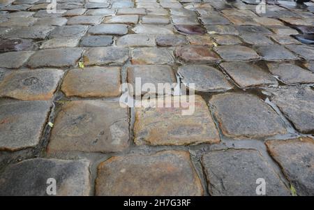 A close-up of a cobbled street in an old town. Wet cobbled road background. Stock Photo