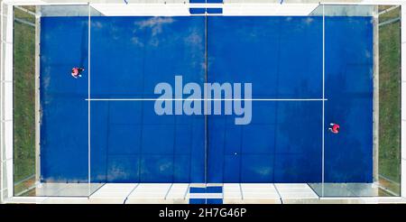 View from above, stunning aerial view of two people playing on a blue padel court. Padel is a mix between Tennis and Squash. It's usually played in do Stock Photo