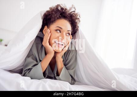 Portrait of attractive cheerful girl lying in bed under duvet good mood enjoying pastime at light home house indoors Stock Photo