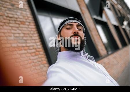 Young man in traditional arabian headwear making selfie Stock Photo