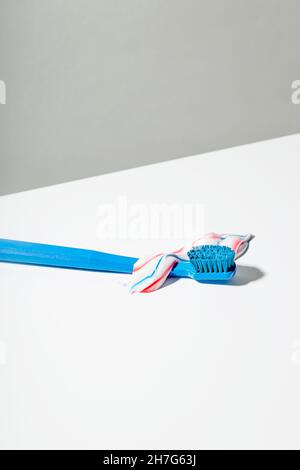 Blue toothbrush with squeezed out red white and blue toothpaste lies on light background Stock Photo