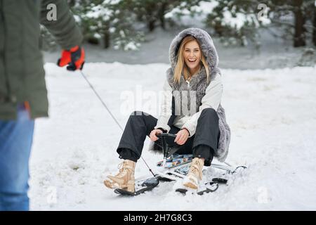Couple having fun with sledge on snow in winter Stock Photo