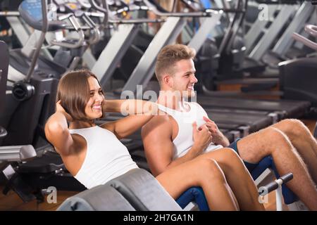 Well trained attractive young man and woman training abdominal muscles in gym Stock Photo