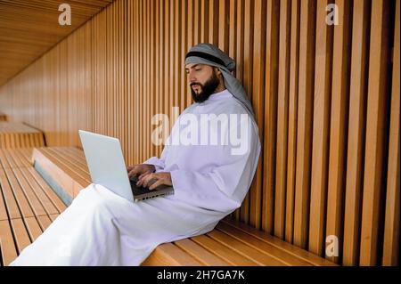 Young arabian businessman working on a laptop and looking involved Stock Photo