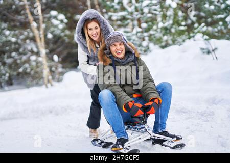 Couple having fun with sledge on snow in winter Stock Photo