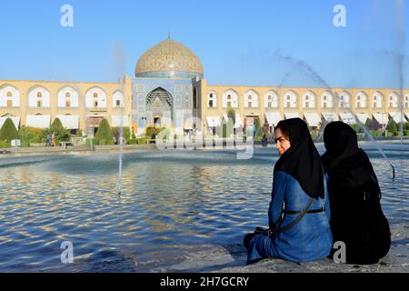 IRAN. ISPAHAN ESFAHAN. WOMEN IN VEIL NEAR THE FOUNTAIN AND THE CHEICK LOFTOLLAH MOSQUE ON EMAM SQUARE. Stock Photo