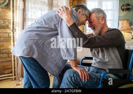 Mature man with disability in wheelchair spending time together with his wife at home Stock Photo
