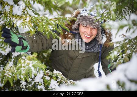 Young handsome man having fun in woods in winter scenery Stock Photo