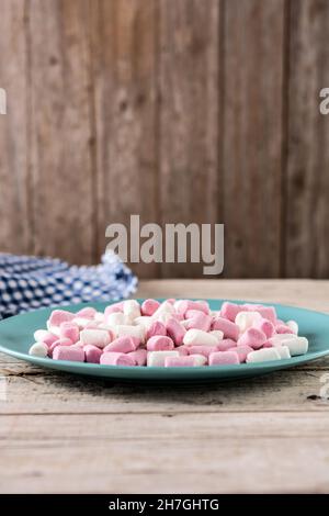 Sweet marshmallows topping in a blue plate on wooden table Stock Photo