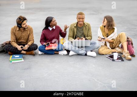 Students sitting and using smartphones on asphalt Stock Photo