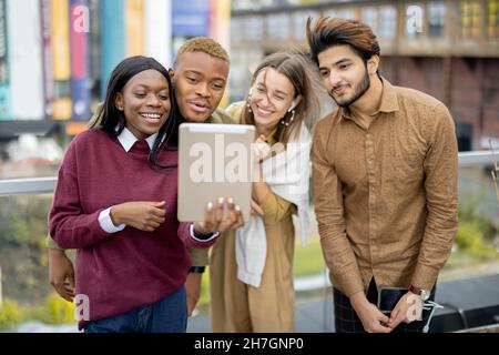 Multiracial students watch some on digital tablet Stock Photo