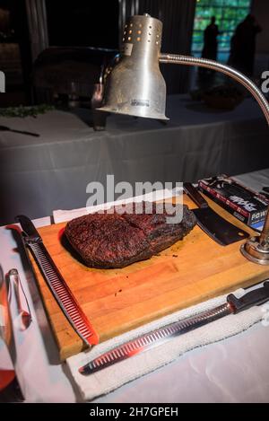 Piece of roast meat on a wooden cutting board in the kitchen Stock Photo