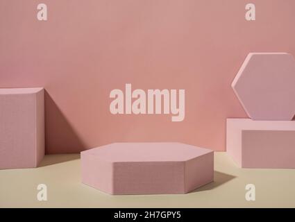 Models of pink geometrical shapes, squares and hexagons, placed on sandy floor against the wall with shadows. Copy space concept Stock Photo