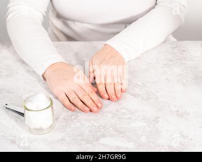 Woman finishing her manicure at home with simple manicure tools