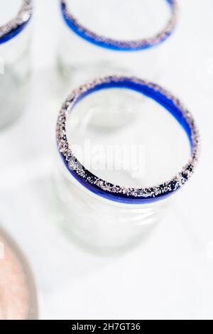 Garnishing edged of the glass with salt for frozen watermelon margarita. Stock Photo