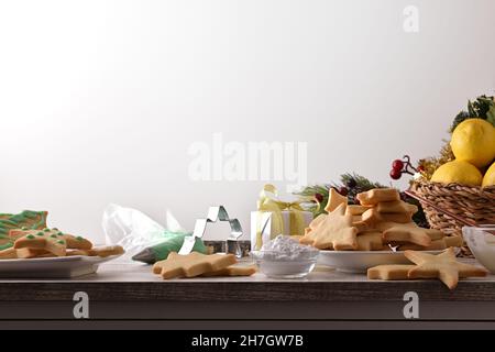 Wooden table with cookies with freshly prepared Christmas shapes on plate with Christmas decoration isolated white background. Front view. Horizontal Stock Photo