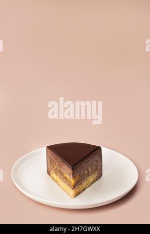 Delicious chocolate mousse cake slice with the layers and texture displayed on pastel coffee colored background. Restaurant menu and confectionery concept. Close-up. Copy space. Stock Photo