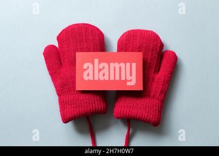 Blank card and winter red knitted gloves on gray background. top view, copy space Stock Photo