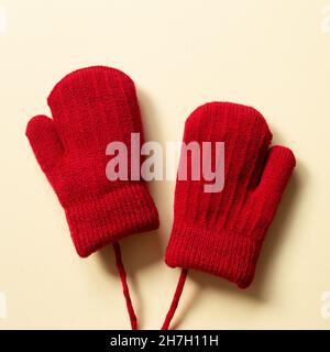 Winter red knitted gloves on beige background. top view, copy space Stock Photo