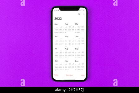 Kharkov, Ukraine - November 17, 2021: Calendar for 2022 on Apple iPhone screen. Calendar application. Purple background, business workspace, top view Stock Photo