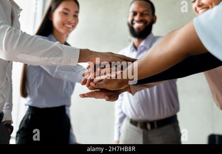 Corporate Traditions. Group Of Happy Multiethnic Collagues Stacking Hands Together Stock Photo