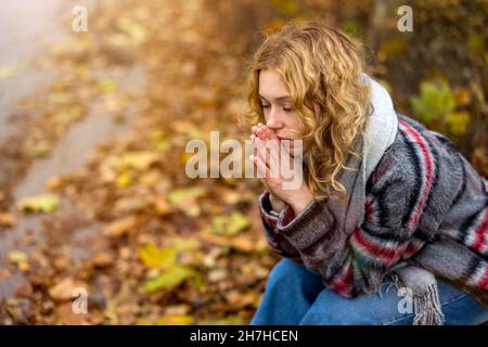 Depressed young woman sitting on bench in a public park Stock Photo