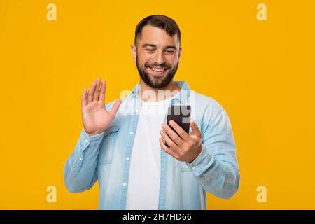 Happy mature handsome caucasian man making video call and waving hand to webcam Stock Photo