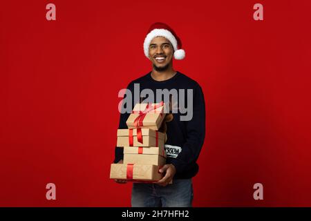 Positive african american man Santa Claus holding presents Stock Photo