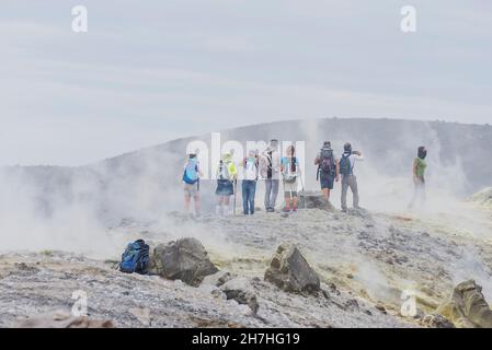 Hikers walking through fumaroles smoke on Gran Cratere rim, Vulcano Island, Aeolian Islands, Sicily, Italy, Stock Photo