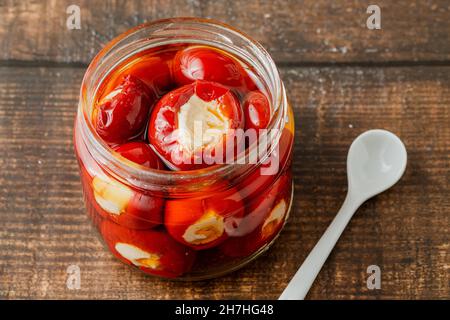 Stuffed cherry peppers with ricotta cheese filling in glass jar on wooden background Stock Photo