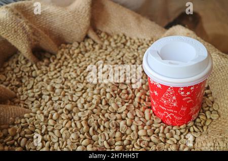 Closeup of a Red and White Takeaway Coffee Cup Isolated on the Pile of Parchment Coffee Beans Stock Photo