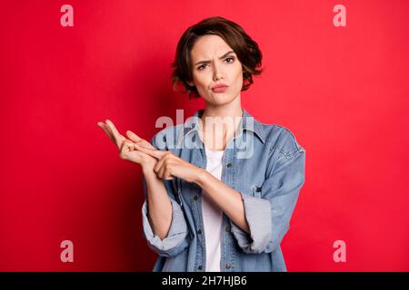 Photo of sad brunette young lady count wear jeans shirt isolated on red color background Stock Photo