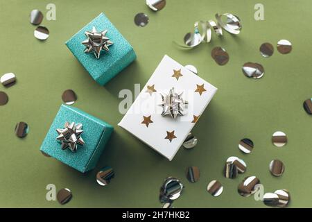 Gift white and green boxes with a tinsel and confetti on a green background. The concept of a gift, a new year, a festive background. Flat lay, top view Stock Photo