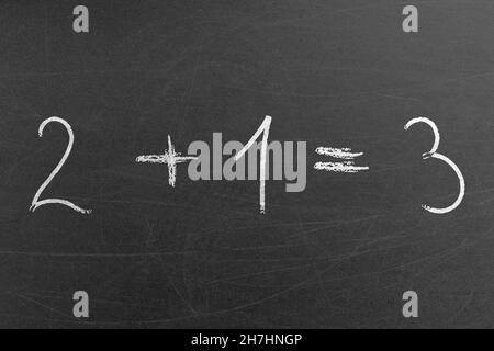 Easy school math equation 2 plus 1 is 3 written on a chalkboard by a student. School and education concepts and backgrounds Stock Photo