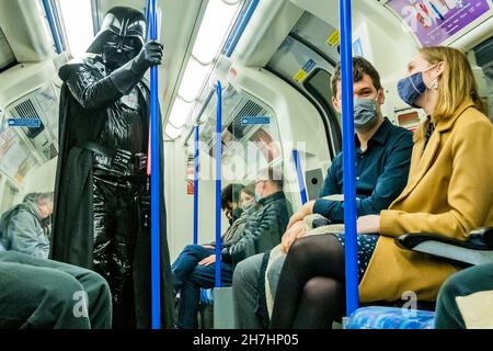 London, UK. 21st Nov, 2021. Taking mask wearing to extremes 'Darth Vader' travels - Mask confusion continues on the underground despite warning signs. The tube is busier and masks are still obligatory but increasing numbers are ignoring the instruction led by mixed messages from the government. Credit: Guy Bell/Alamy Live News Stock Photo