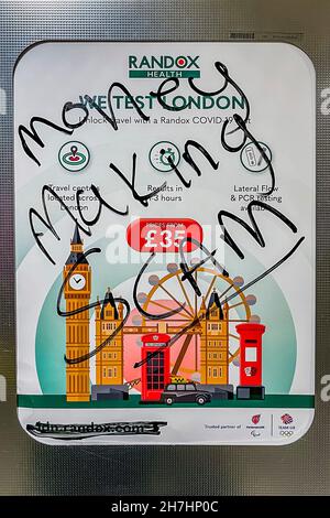 London, UK. 23rd Nov, 2021. Money Making scam graffiti on a We test London for £35 promotion - A Randox testing advert is defaced on the tube by anti vaxers. Credit: Guy Bell/Alamy Live News Stock Photo