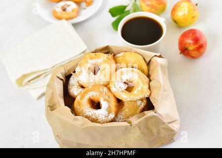 Donuts with powdered sugar in paper bag. Apple rings Stock Photo