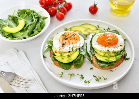 Bread with fried eggs, avocado and greens, close up Stock Photo