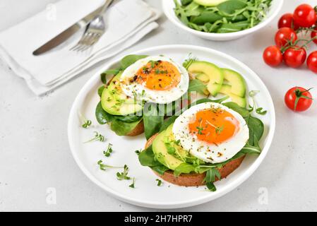 Bread with fried eggs, avocado and greens. Healthy breakfast Stock Photo