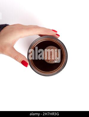 Female hand with red matte manicure holds a glass of coffee top view. Isolated on white background. Close up. Enjoy a cup of coffee concept Stock Photo