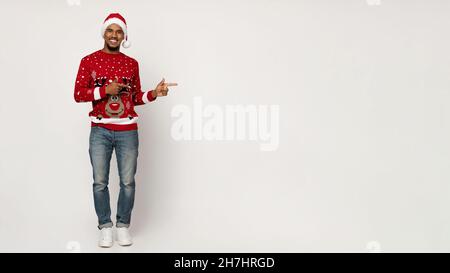 Positive black guy in Santa hat pointing at copy space Stock Photo