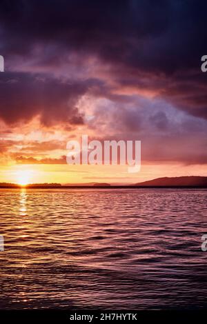 Sunset golden hour at Nelson Bay with storm clouds rolling in over the water. Stock Photo