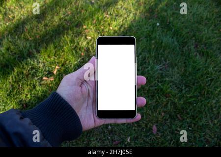 Mockup image of man hand holding black smartphone with blank white screen on the nature background. Stock Photo