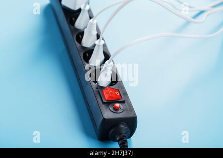Surge protector with connected white wires of electrical appliances on a blue background. Free space Stock Photo