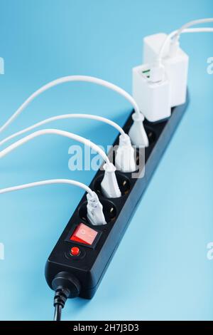 Surge protector with connected white wires of electrical appliances on a blue background. Free space Stock Photo