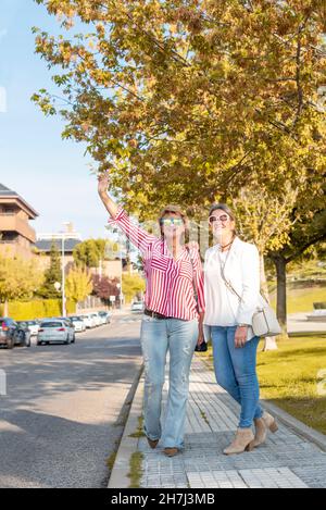 Two middle-aged Caucasian women on the street hailing a cab Stock Photo