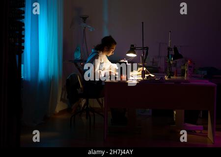 Tailor studio with designer creating clothes. Creative female dressmaker sewing on sewing machine Stock Photo