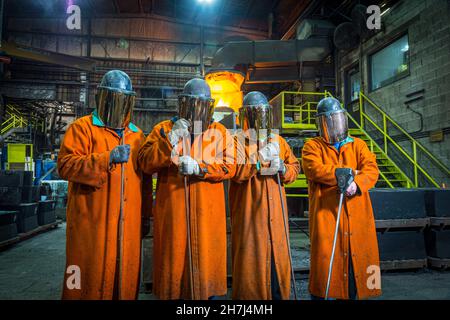 Four workers in protective safety equipment inside steel mill, Pennsylvania, USA
