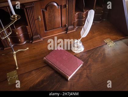 Quill pen and ink with book on vintage antique desk Stock Photo