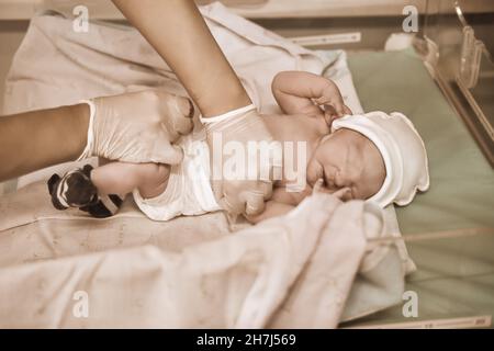 Dressing a newborn baby by a doctor immediately after delivery Stock Photo